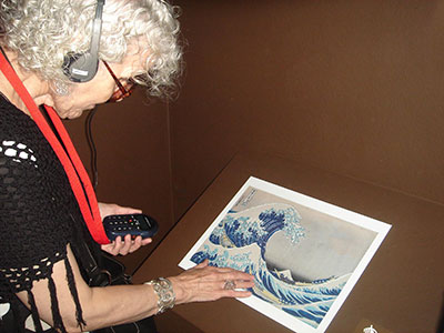 A blind visitor listening to the audioguide while exploring a tactile diagram